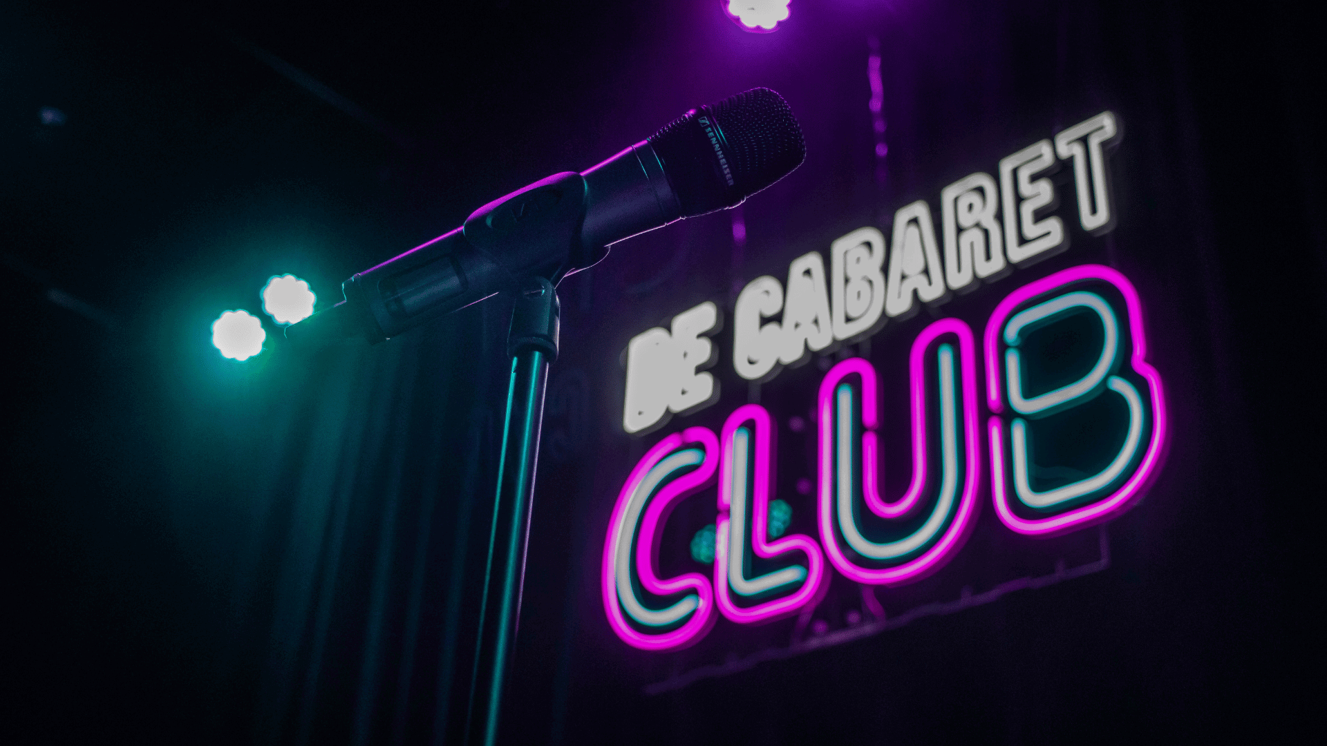 Microfoon op voorgrond, led verlichting met tekst "de cabaret club" op de achtergrond
