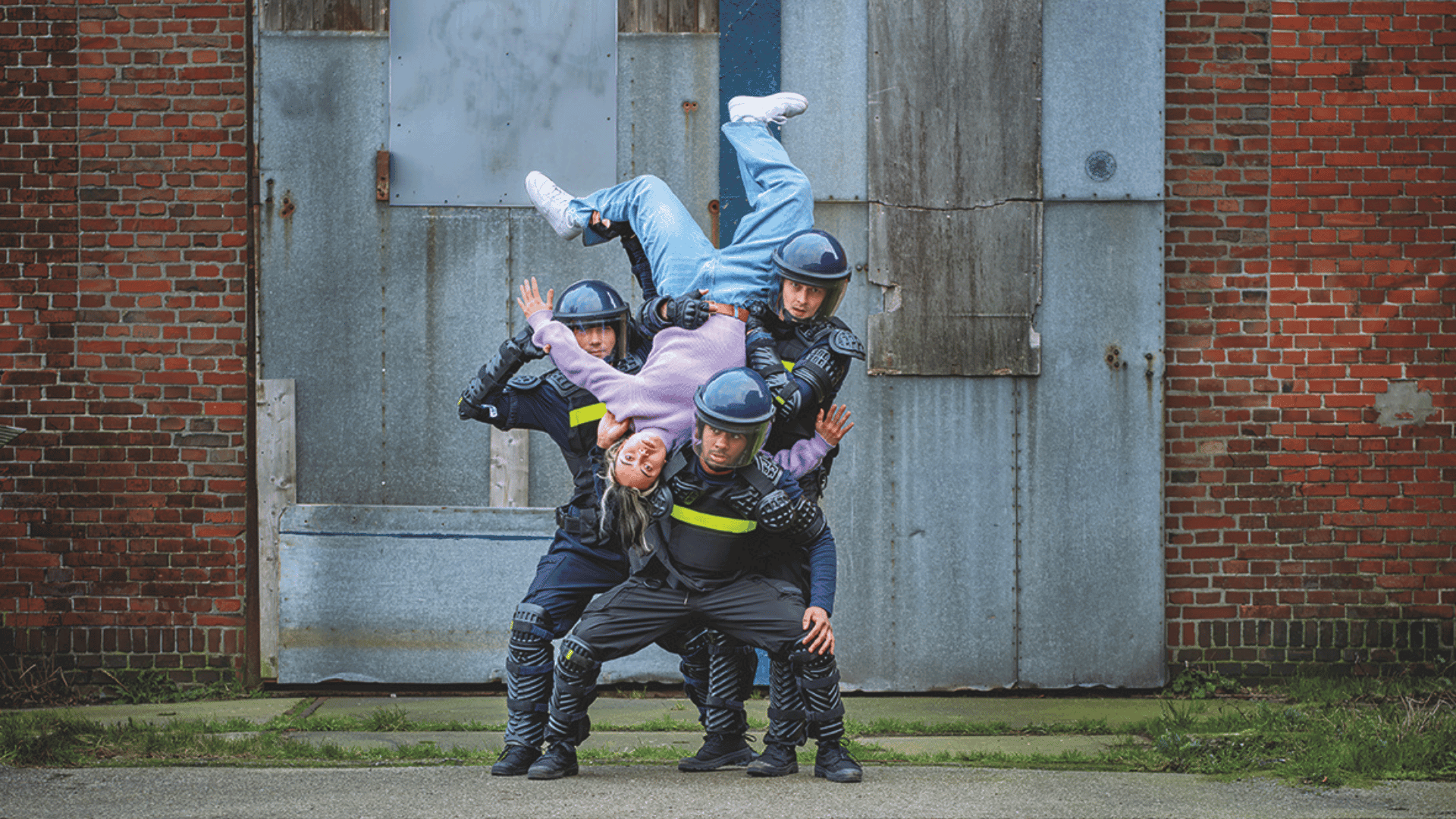 Vrouw hangt op de kop op drie mannen die een helm en uniform dragen