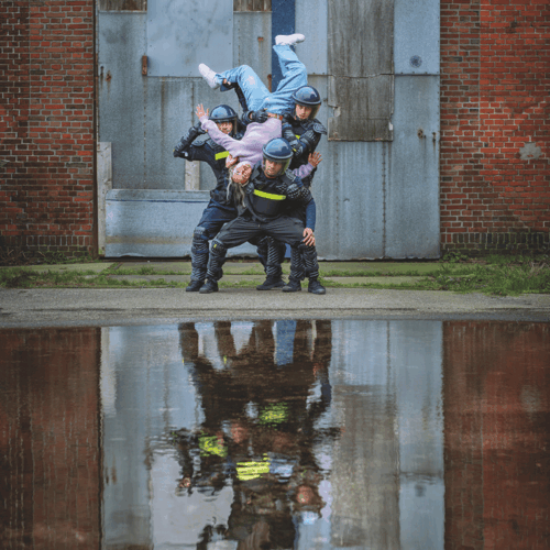 Vrouw hangt op de kop op drie mannen die een helm en uniform dragen