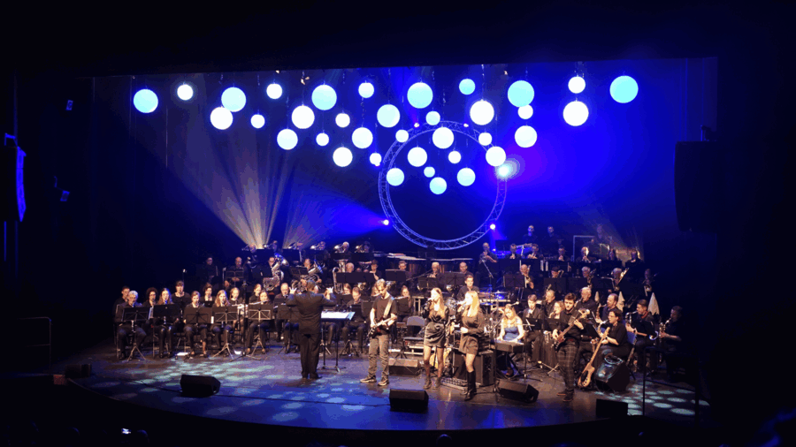 podium gevuld met verschillende mensen met instrumenten en dirigent