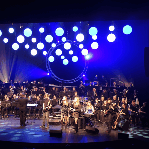 podium gevuld met verschillende mensen met instrumenten en dirigent