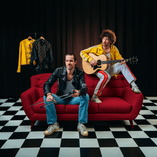 2 mannen op rode bank, een zit op de leuning met een gitaar
